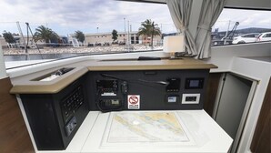 De bedieningspost van een boot, met een kaart, communicatieapparatuur en een bord met 'Niet roken'.