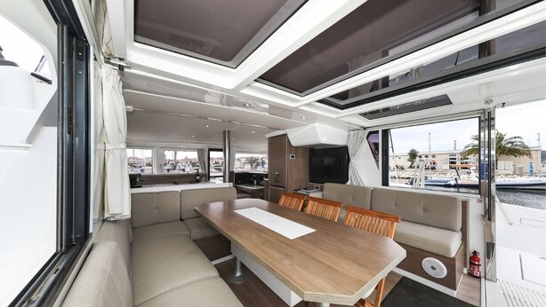 Een modern interieur met een lange eettafel, zachte zitplaatsen en grote ramen met uitzicht op de jachthaven.