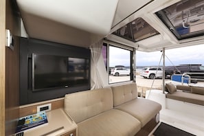 Ein modernes Wohnmobil-Interieur mit einem großen Flachbildfernseher, einer Sitzecke und einem Essbereich.