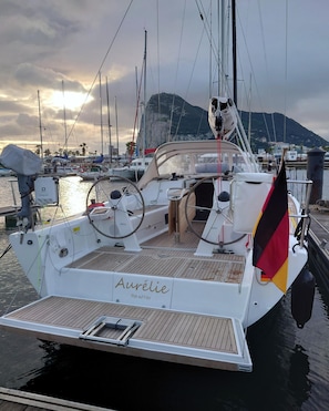 Ein Segelboot liegt in einer Marina vor einer Berglandschaft.