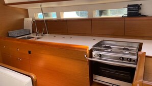 Une petite cuisine fonctionnelle avec un fourneau en acier inoxydable, un évier et des meubles de rangement en bois.