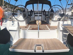 A boat deck with a steering wheel, a small table, and a life preserver. - Sun-soaked Sailing Adventure in the Ionian Islands (Perigiali)