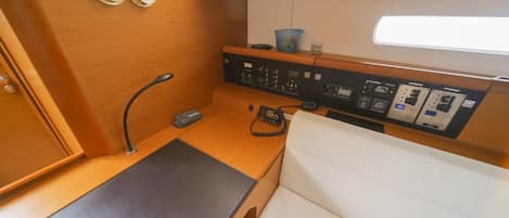 A compact control panel with various switches and dials, a small table, and a white cushioned seat.