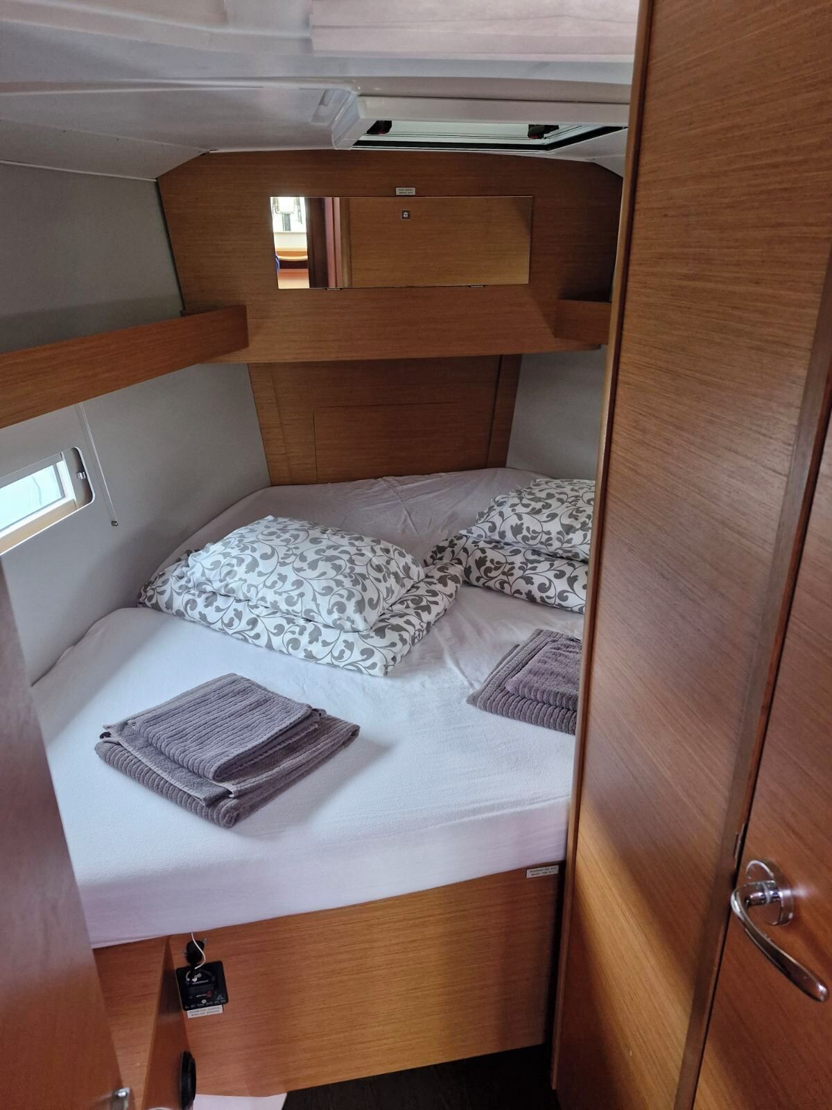 A compact RV interior with a bunk bed, a small window, and a door.