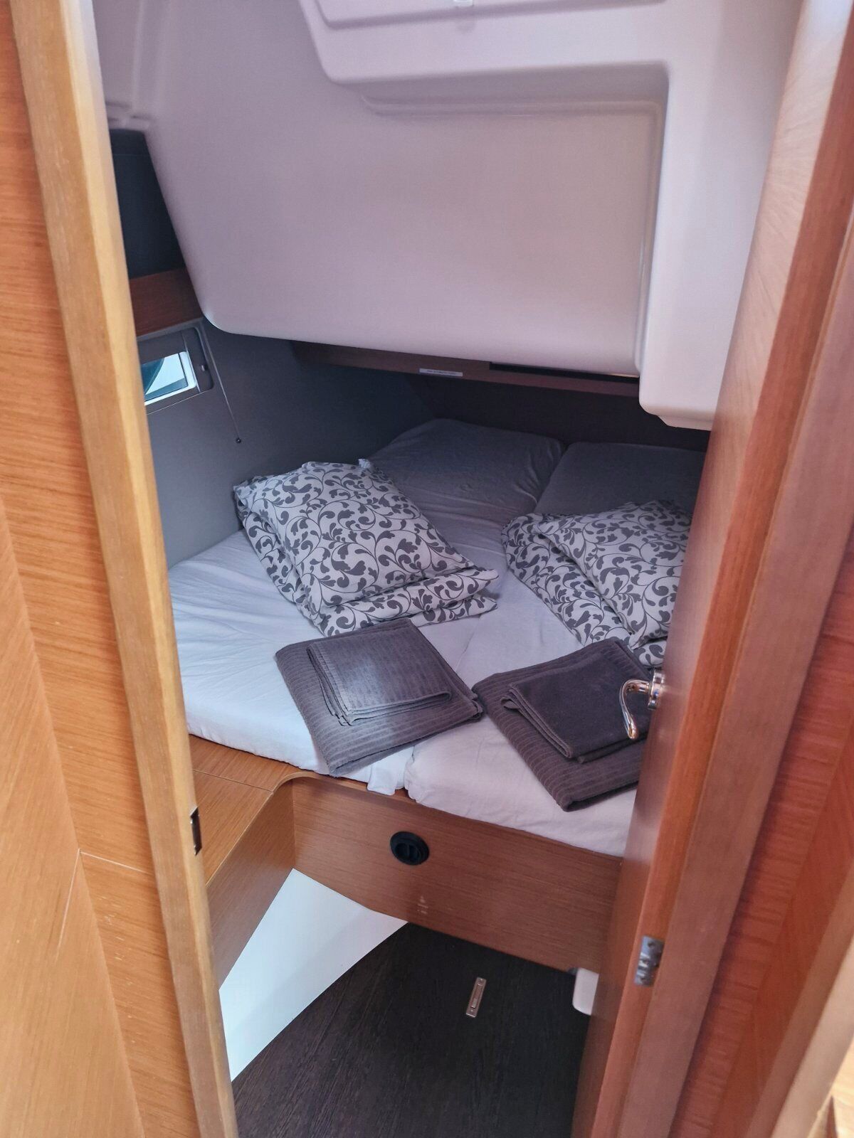 A compact, well-organized sleeping area with a bunk bed, a small window, and a storage compartment.