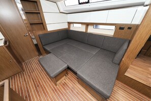 Een compact interieur met slaapbank, houten vloeren en inbouwkasten.