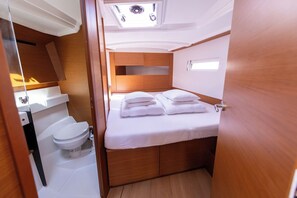 Een compacte, goed verlichte kamer met een bed, een klein raam en een dakraam.