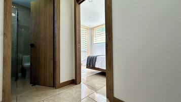 Un pasillo con una puerta de madera que da a un baño y un dormitorio.