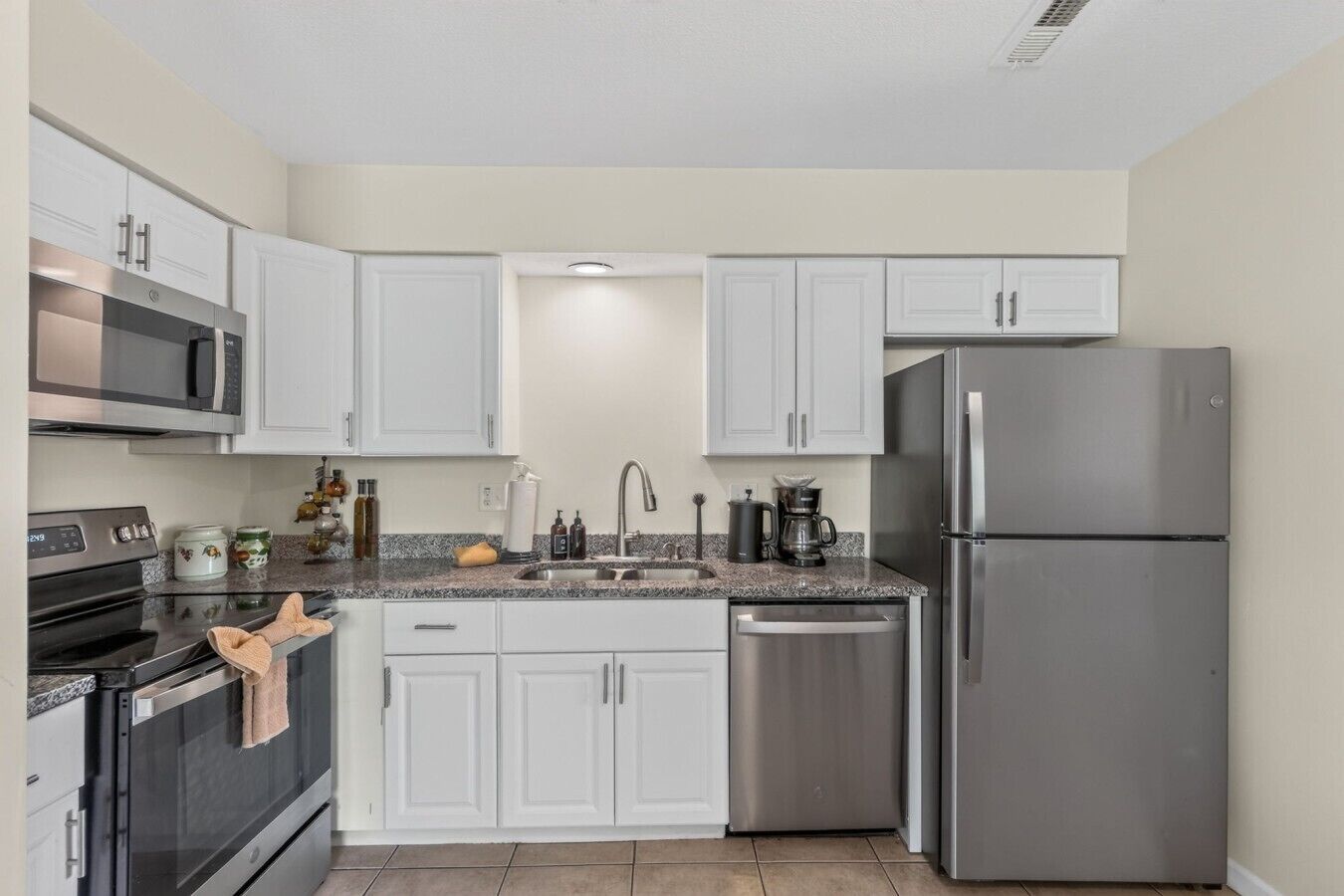 A kitchen with white cabinets, stainless steel appliances, a granite countertop, and a dishwasher.