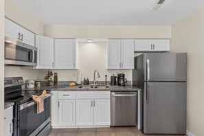 A kitchen with white cabinets, stainless steel appliances, a granite countertop, and a dishwasher.