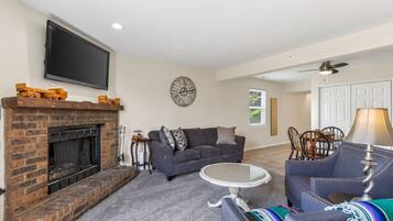A living room with a fireplace, a sofa, a coffee table, and a television mounted on the wall.