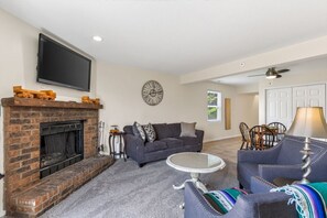 A living room with a fireplace, a sofa, a coffee table, and a television mounted on the wall.