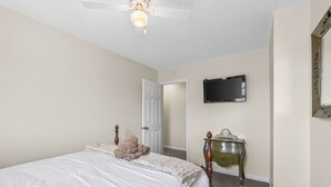 A bedroom with a bed, a dresser, a ceiling fan, and a television on the wall. - Remote Work Ready | 3BR | Google Fiber | Kings (Lee`s Summit)