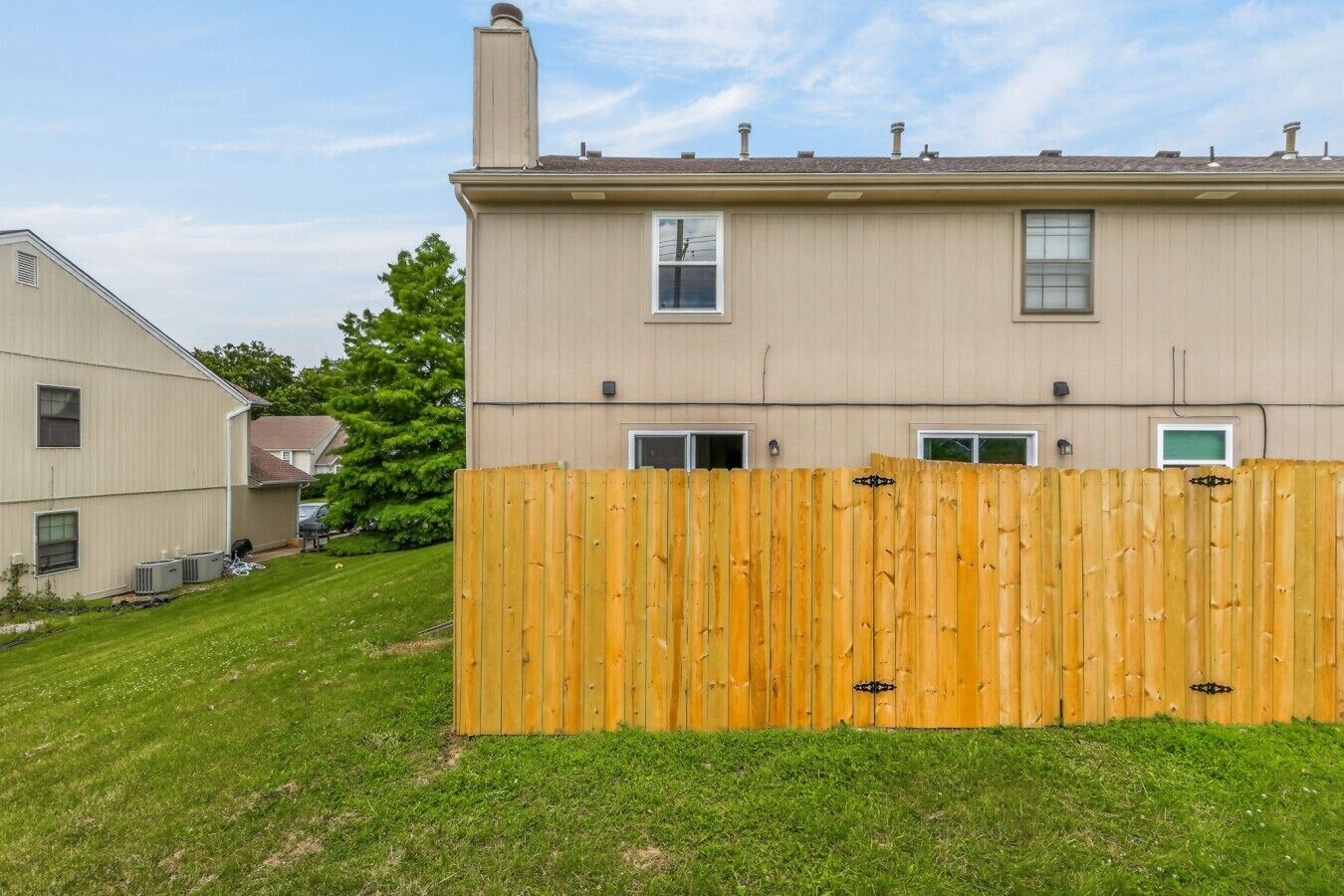 A two-story residential building with a wooden fence in front.