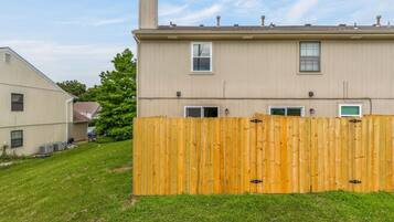 A two-story residential building with a wooden fence in front.