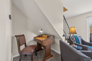 A corner room with a desk, chair, and a staircase.