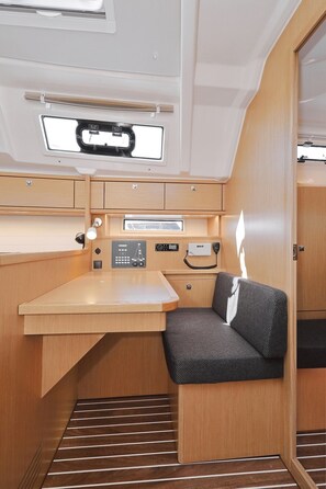 A compact interior with a wooden desk, a cushioned seat, a control panel, and a small window. - Sun-Kissed Sailing Adventure in Zadar, Croatia (Biograd na moru)
