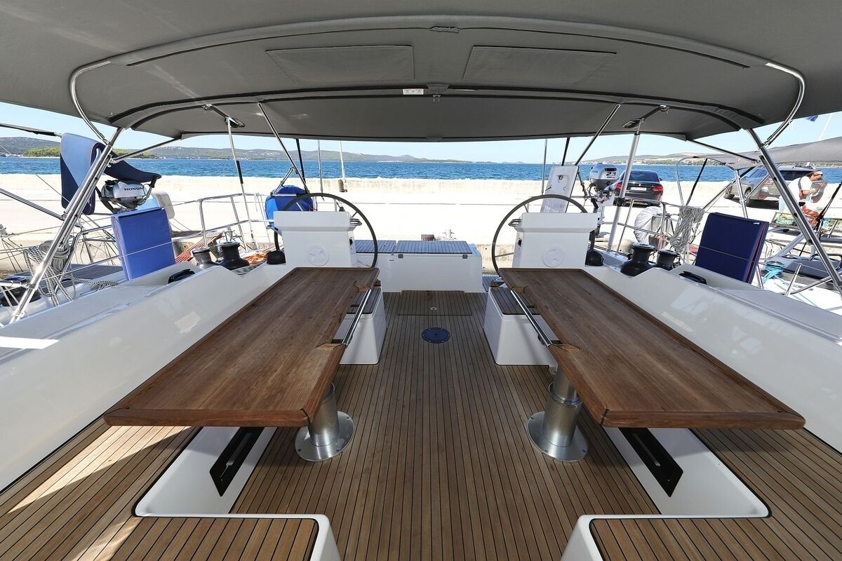 Cubierta de barco con una mesa central, asientos y vista al mar.