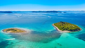 An aerial view of a coastal area with two islands, clear turquoise waters, and distant landforms. - Sun-Kissed Sailing Adventure in Zadar, Croatia (Drage)