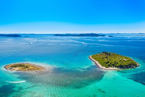 An aerial view of a coastal area with two islands, clear turquoise waters, and distant landforms. - Sun-Kissed Sailing Adventure in Zadar, Croatia (Drage)