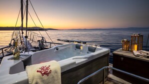 Ein Bootsdeck mit einem Whirlpool, einem Holztisch mit einer Laterne und einer gemütlichen Sitzecke.