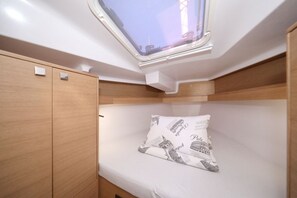 Een stapelbed met dakraam, een houten garderobe en een kussen met bedrukking.