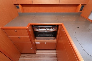 A compact kitchen with built-in appliances, wooden cabinetry, and a countertop.