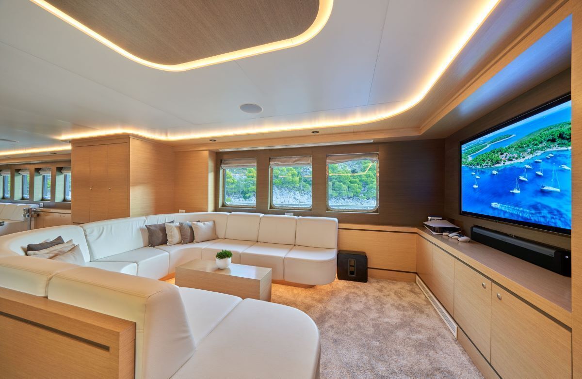 Una sala de estar moderna con un televisor de pantalla plana grande, un sofá blanco modular y un ventanal con vista al mar.