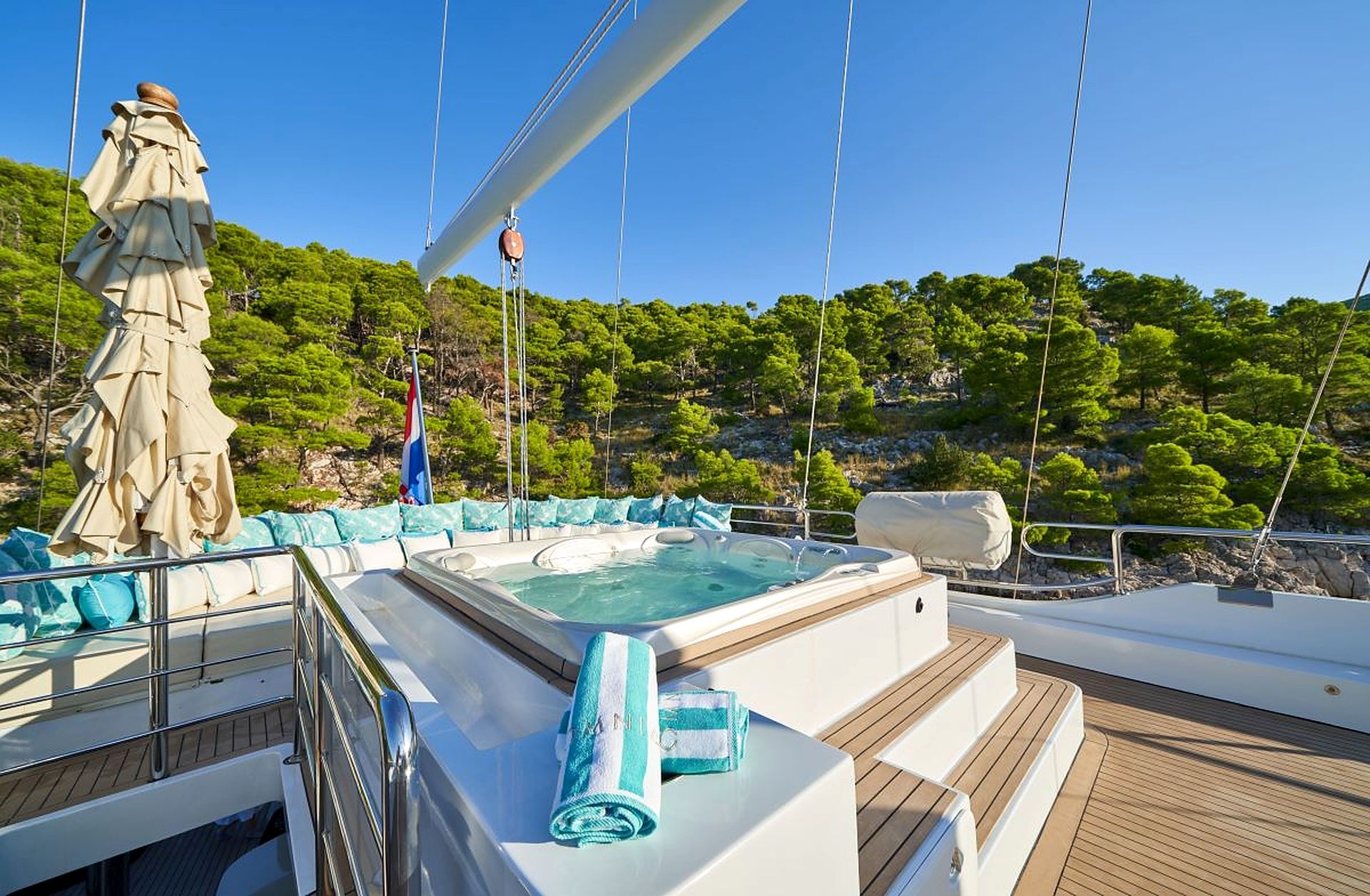 A yacht deck with a hot tub, lounge chairs, and a statue.