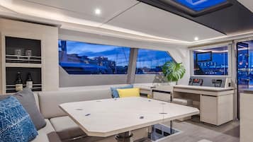 Un intérieur de yacht moderne comprenant un espace repas, des sièges et un poste de commande.