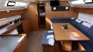A compact galley with a wooden countertop, a bench, and a table with cushions. - Sun-Kissed Sailing Adventure in Zadar, Croatia (Drage)