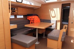 A compact RV interior with a dining area, seating, and a storage cabinet. - Sun-Kissed Sailing Adventure in Zadar, Croatia (Biograd na moru)