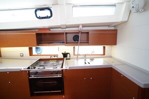 A compact galley kitchen with a stove, oven, and sink.