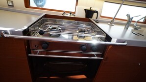 Cozinha com fogão, forno e uma janela acima do balcão.