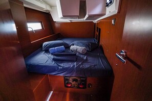 A compact cabin with a bed, control panel, and a small window.