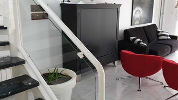 Een moderne woonkamer met een trap, een zwarte kast, een rode stoel en een potplant.