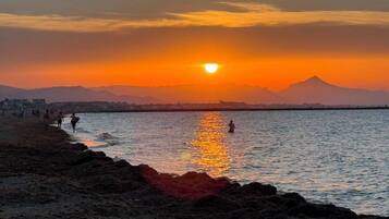 Een zonsondergang boven een wateroppervlak, met een berg op de achtergrond.