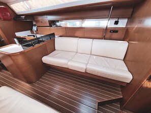 A compact galley with a white cushioned bench, wooden cabinetry, and a small kitchen area. - Sun-Kissed Sailing Adventure in Sibenik, Croatia (Rogoznica)