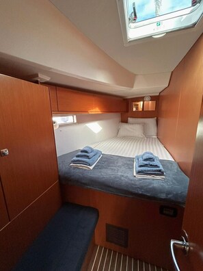 A compact cabin with a bunk bed, a small seating area, and a window with a view of the sky. - Sun-Kissed Sailing Adventure in Islas Sarónicas (Alimos)