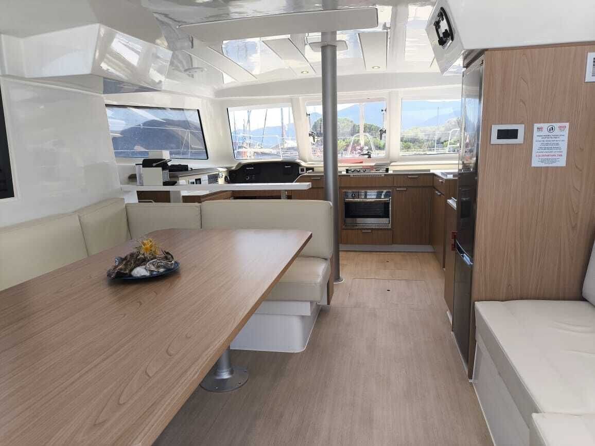 Un intérieur de bateau compact comprenant un coin repas, un coin cuisine et un espace salon.