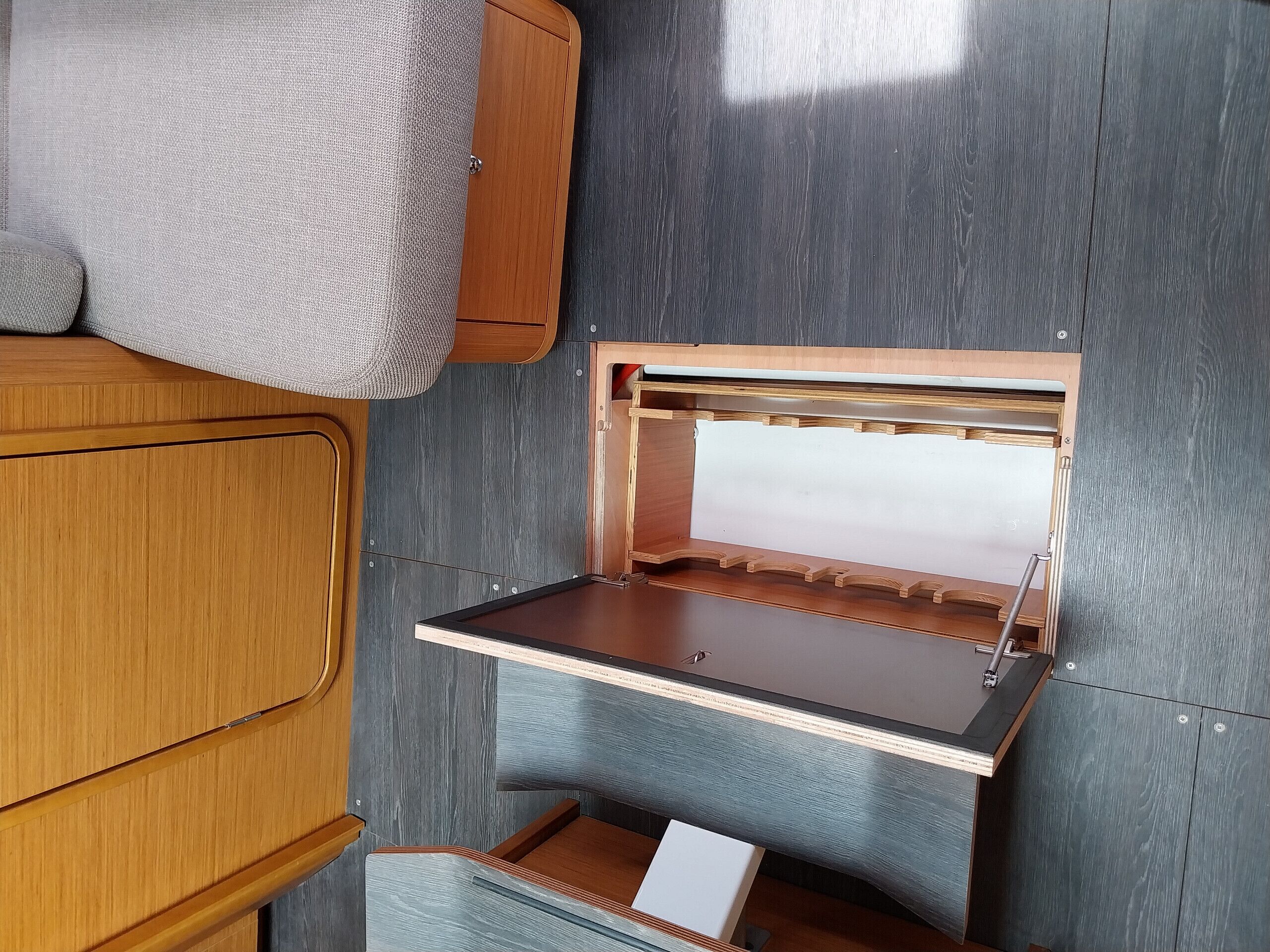 A compact, well-organized interior with a wooden cabinet, a small table with a white surface, and a built-in shelf with hooks.
