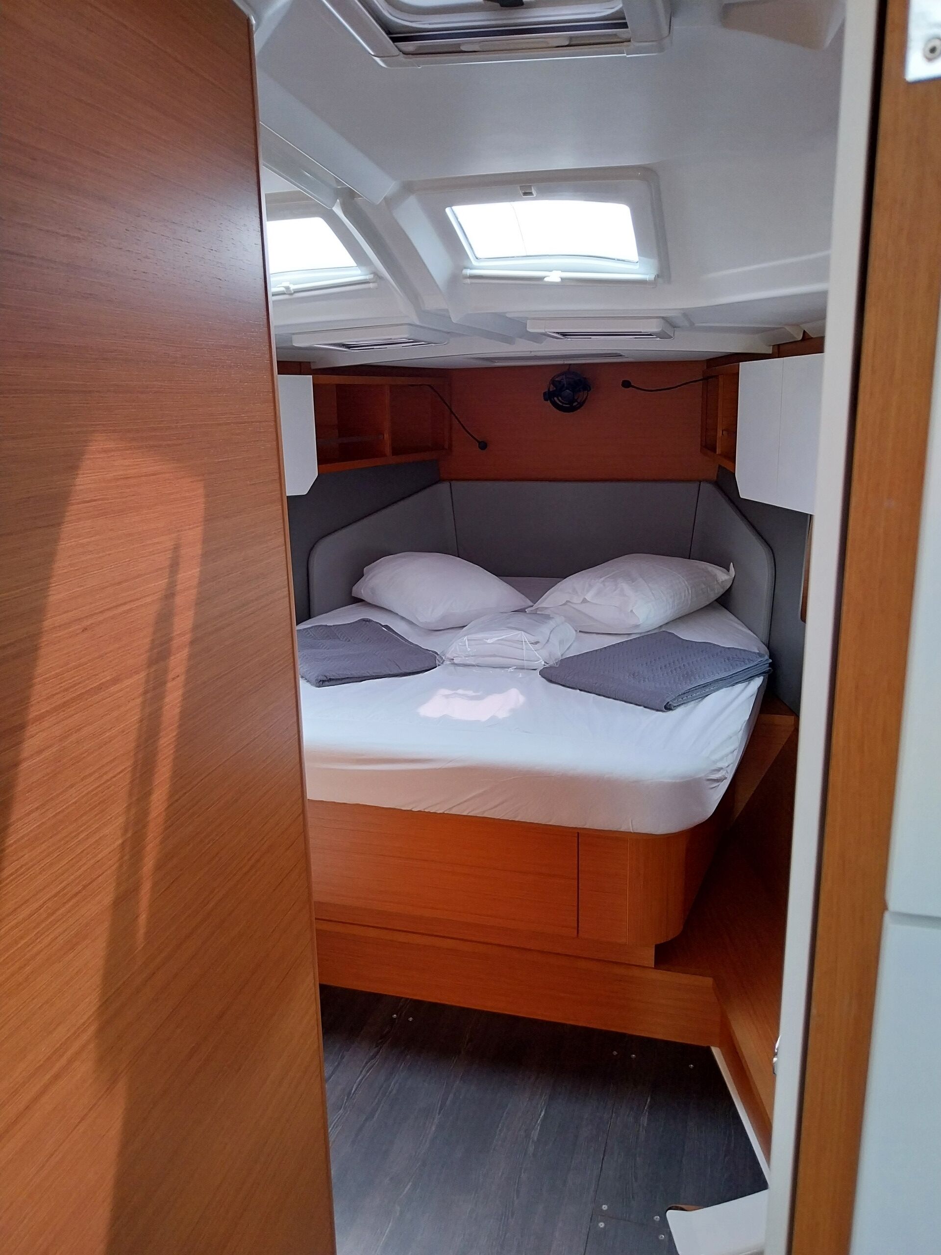 A compact bed with a headboard, a skylight above, and a wooden floor.