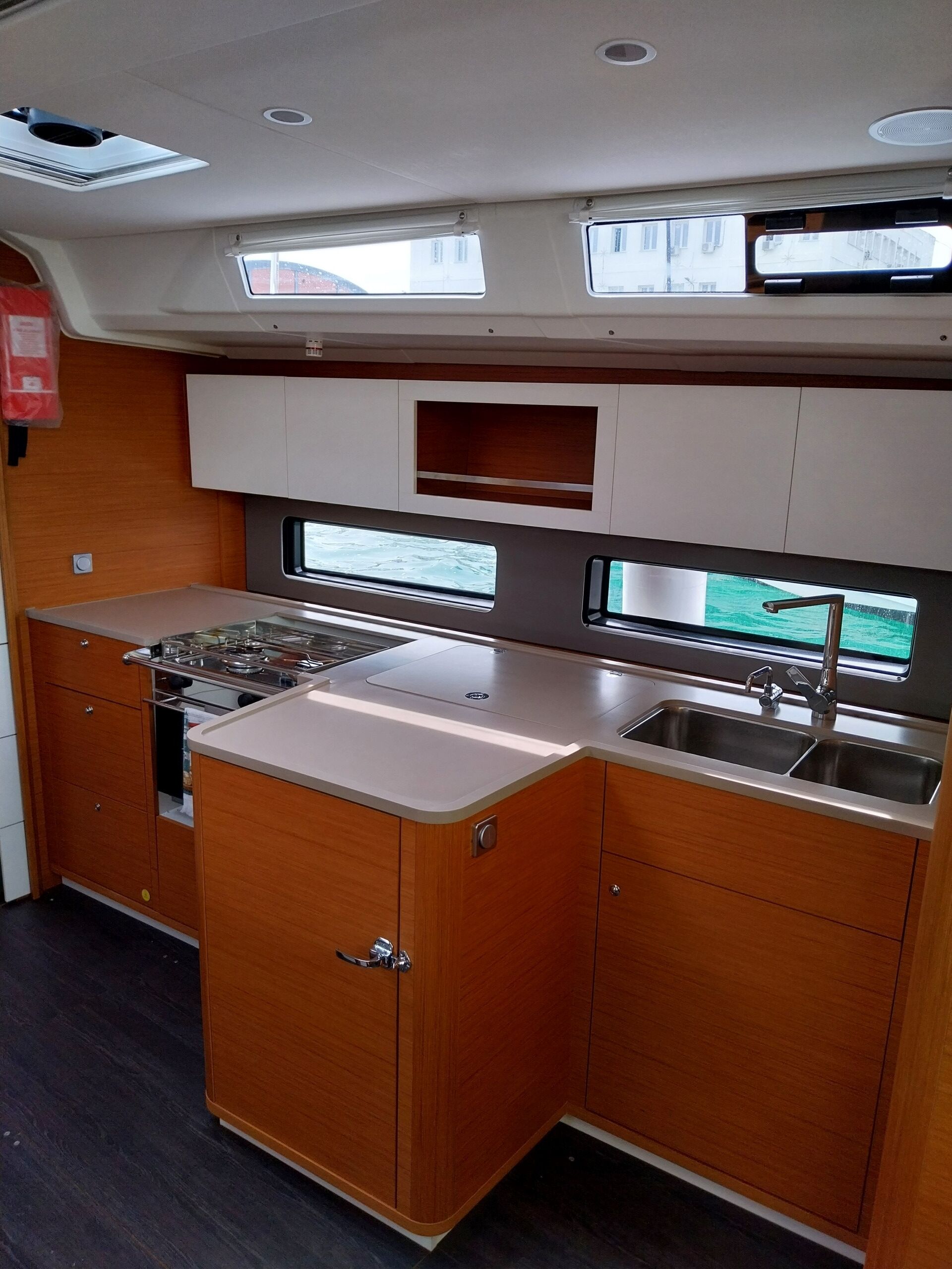 A compact kitchen with a stove, sink, and upper cabinets.