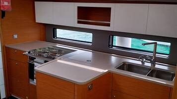 A compact kitchen with a stove, sink, and upper cabinets.