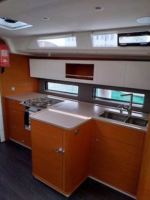 A compact kitchen with a stove, sink, and upper cabinets.