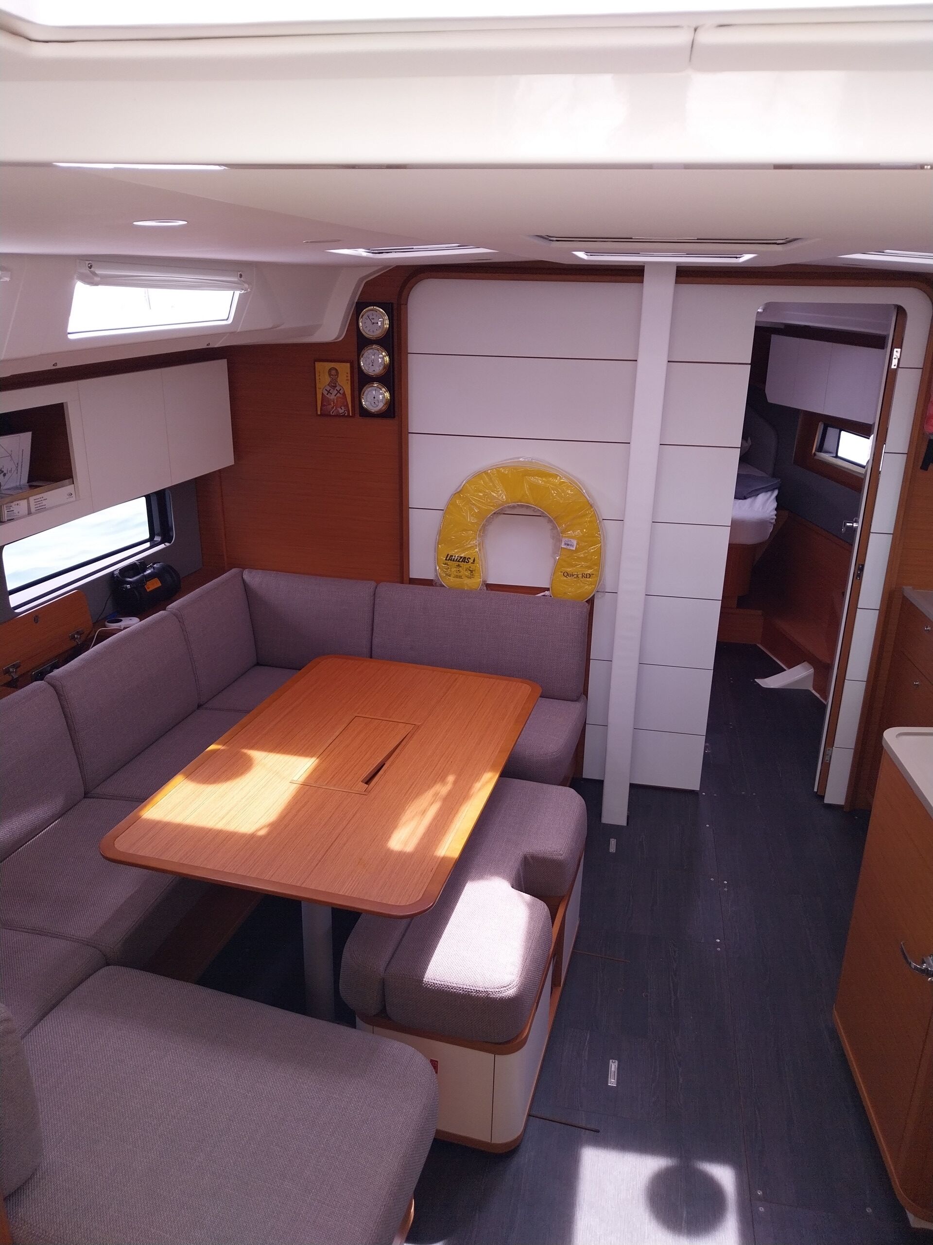 A compact interior with a wooden table, cushioned seating, a small kitchenette, and a toilet.