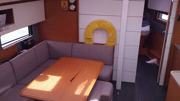A compact interior with a wooden table, cushioned seating, a small kitchenette, and a toilet.
