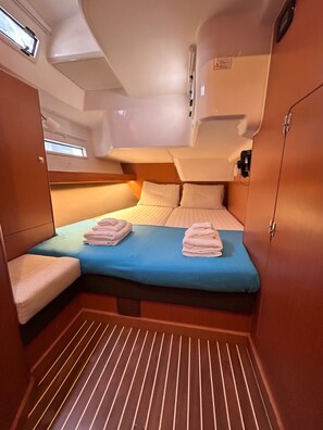 A compact, well-lit cabin with a single bed, a small seating area, and a window.