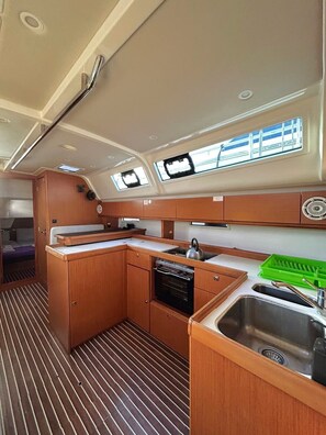 A compact galley with a sink, stove, and storage cabinets.