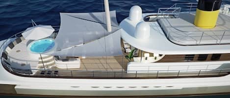 A yacht with a swimming pool, sun loungers, and a covered seating area.